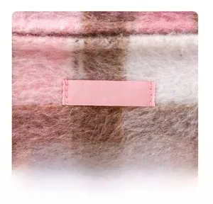 Detalle del neceser de felpa a cuadros con etiqueta de marca y textura suave