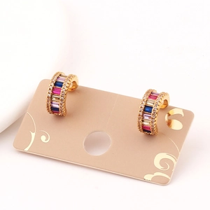 Detail of C-shaped gold hoop earrings with multi-colored rectangular gemstones on card
