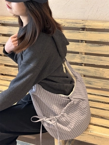 Detail of purple plaid nylon crossbody bag with drawstring bow and zipper closure