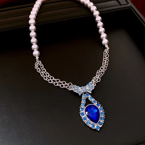 Close-up of blue teardrop pendant necklace with pearl beads in luxury jewelry box