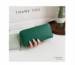 Litchi texture emerald green long zip wallet held by a model with elegant background