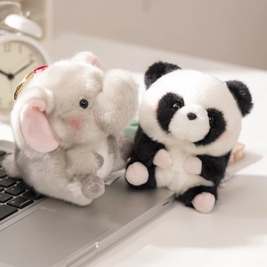 Cute plush elephant and panda dolls placed on a laptop in a cozy indoor setting