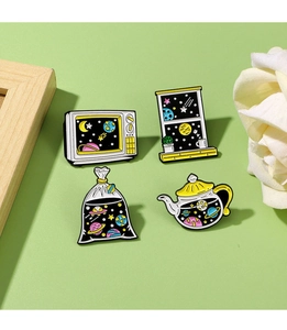 Detail shot of four starry space enamel pins featuring TV, window, and teapot designs