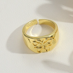 Close-up of golden adjustable ring with embossed butterfly pattern on white leather background