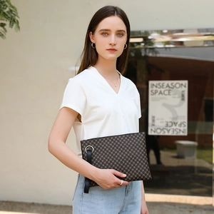 Minimalist crocodile pattern handbag with gold accents held by model in outdoor setting