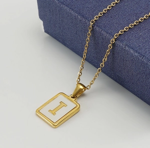 Détail du pendentif lettre I dorée avec nacre blanche sur un écrin à bijoux bleu foncé