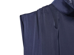 Dettaglio dell'abito in raso blu navy con eleganti pieghe sulle spalle e collo alto