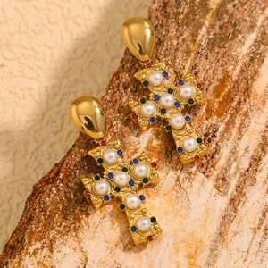 Macro shot of 18K gold vintage cross earrings with white pearls and colorful gemstones
