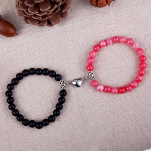 Detail of beaded magnetic bracelets for couples with black and pink stones on burlap background