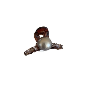 Brown tortoiseshell hair claw clip with central pearl and rhinestone accents on white background