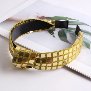 Detailed view of wide gold sequin headband with glittering fabric and black inner lining