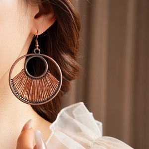 Macro detail of vintage bronze hollow earring with brown woven fan pattern on model