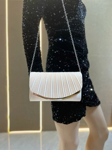 Detail of pleated cream evening bag with gold metal trim and silver chain strap