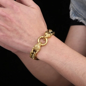 Détail du fermoir tête de loup en or poli sur un bracelet gourmette en acier de style punk
