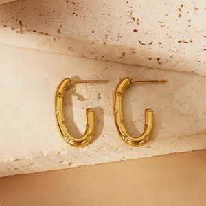 Close-up of golden U-shaped earrings with textured geometric triangle patterns