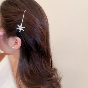 Detail of silver snowflake hair clip with white crystals styled on long wavy hair
