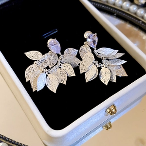Close-up of silver drop earrings with purple zircon stones and hollowed leaf tassels