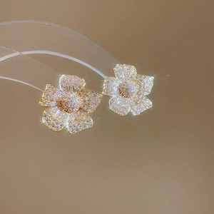 Detailed macro view of golden flower earrings featuring sparkling zircon pave settings
