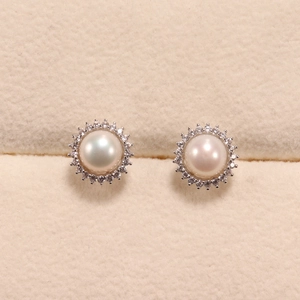 Elegant freshwater pearl stud earrings with zircon halo on beige velvet jewelry box