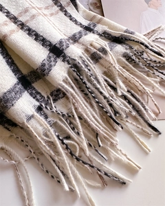 Close-up of soft plaid scarf fabric texture and long fringe details in black and beige