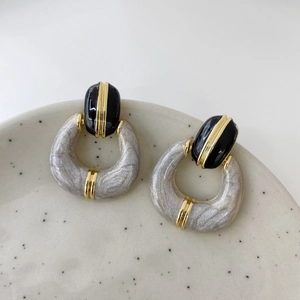 Detail of vintage French enamel earrings with black oval and grey U-shaped resin drop