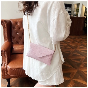 Detailansicht der rosa Umschlagtasche mit Glitzertextur und feinem goldenem Kettenriemen