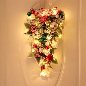 Detail of Christmas teardrop wreath with red bows, ornaments, and warm LED lights