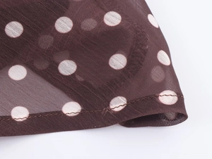 Détail du tissu en maille marron à pois blancs et finitions soignées des coutures