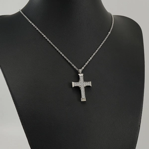 Close-up of a silver cross pendant necklace with sparkling rhinestones on a mannequin