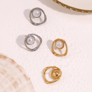 Flat lay of irregular hollow gold and silver earrings with pearls on water ripple background