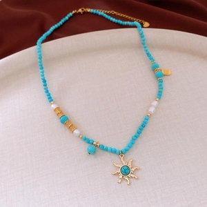Detail of sun pendant necklace with turquoise beads, pearls and golden Fu character charm