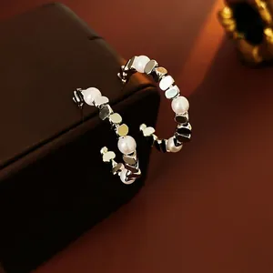 Minimalist pearl hoop earrings with metallic square accents on dark jewelry box