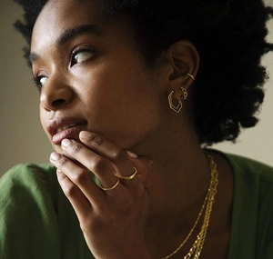 Detailed view of model wearing a gold geometric necklace, earrings and ring set