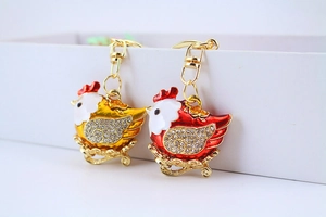 Detail of red and gold metal rooster keychains with enamel and crystal rhinestones