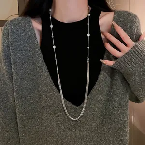 Long multilayer pearl necklace on grey cardigan for elegant layered sweater look