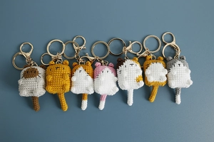 Row of seven colorful handmade crochet animal keychains with gold metal hooks