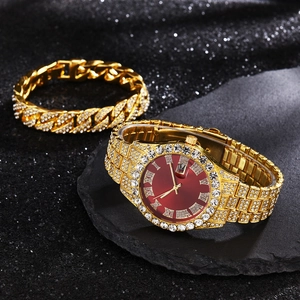 Close-up of luxury gold watch with red dial and iced-out Cuban bracelet on dark rock