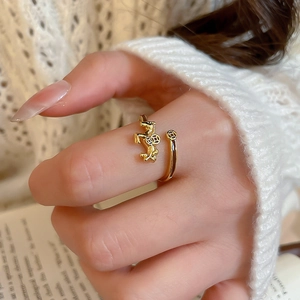 Macro shot of gold-plated horse ring on model's hand with white sweater and book