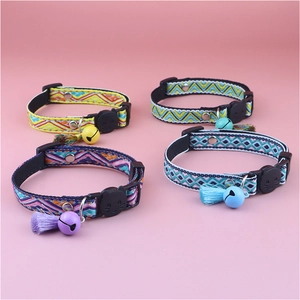 Detail of four colorful patterned cat collars with tassels and bells on a pink backdrop