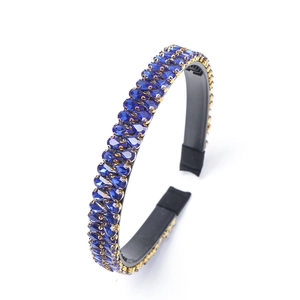 Baroque style gold headband with brilliant blue rhinestones on a white background