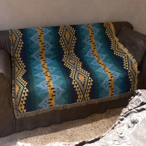 Bohemian geometric ethnic picnic mat with fringes on a leather sofa outdoors