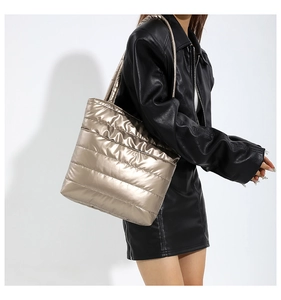 Close-up of metallic champagne gold quilted tote bag with shiny puffer texture on model