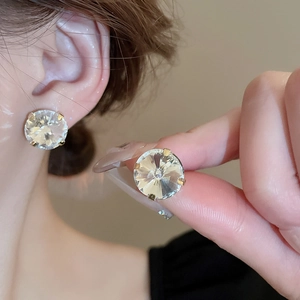 Close-up of golden claw-set heart stud earring with large clear sparkling rhinestone
