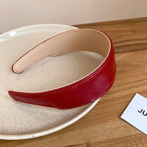 Detail of red faux leather pleated headband on a ceramic plate with warm lighting