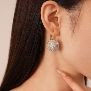 Boucles d'oreilles boules en cristal brillant doré portées par un mannequin