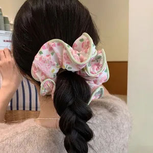 Pink floral print oversized scrunchie with light green piping on a braided hairstyle