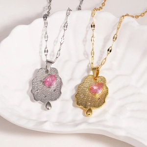 Cloud pendant necklace set in gold and silver with pink gemstones on ceramic plate
