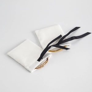 White velvet drawstring jewelry pouch with luxury gold diamond bracelets inside