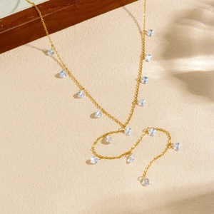 Gold plated stainless steel necklace with water drop zircon pendants on a light background