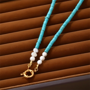 Artistic turquoise beaded necklace with freshwater pearls and gold spring clasp on velvet